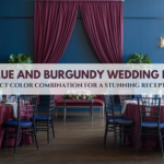 Navy blue and burgundy wedding reception decor with elegant table settings and drapery.