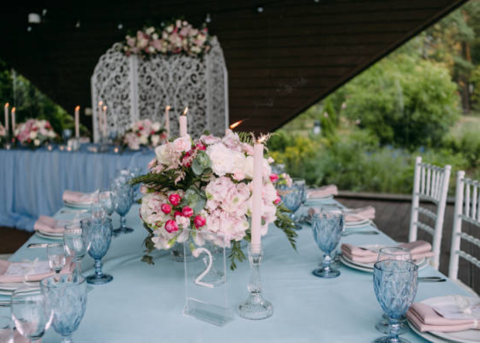 Reception table setup with dusty blue linens, soft candlelight, and dusty rose floral centerpieces creating an elegant atmosphere.